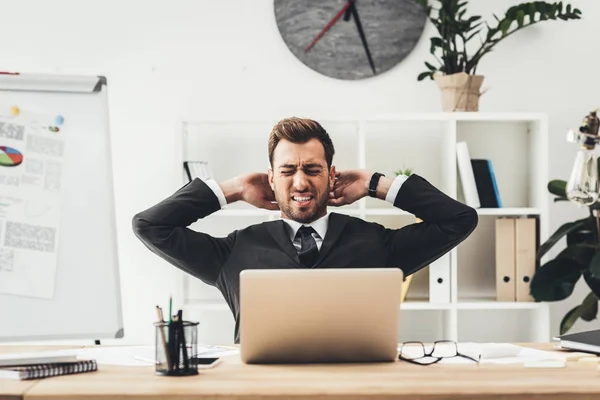 Tired businessman stretching at workplace — Stock Photo, Image