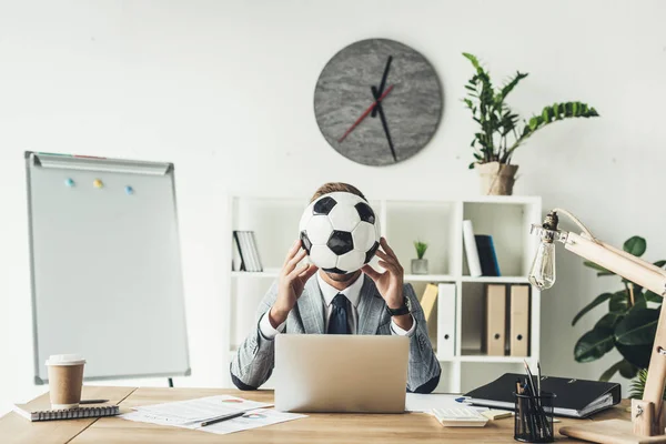 Homem de negócios cobrindo rosto com bola de futebol — Fotografia de Stock