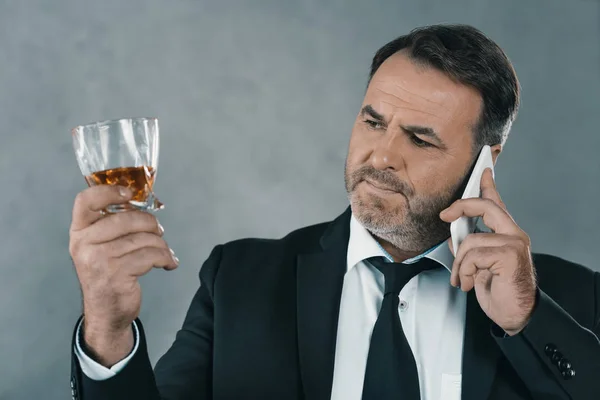 Бизнесмен со стаканом виски разговаривает по телефону — стоковое фото
