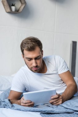 Adam yatakta dijital tablet kullanma
