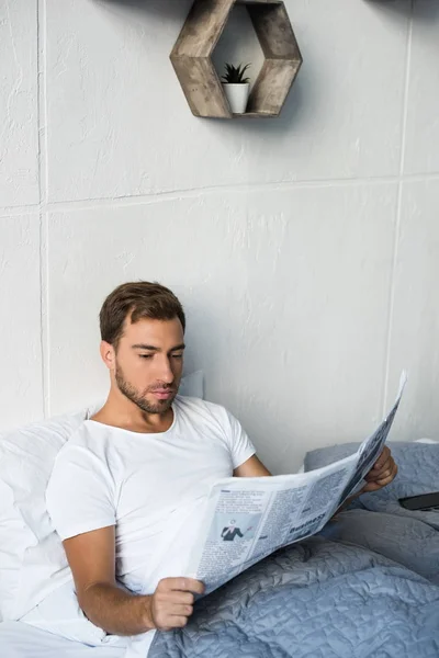 Man in bed reading newspaper — Stock Photo, Image