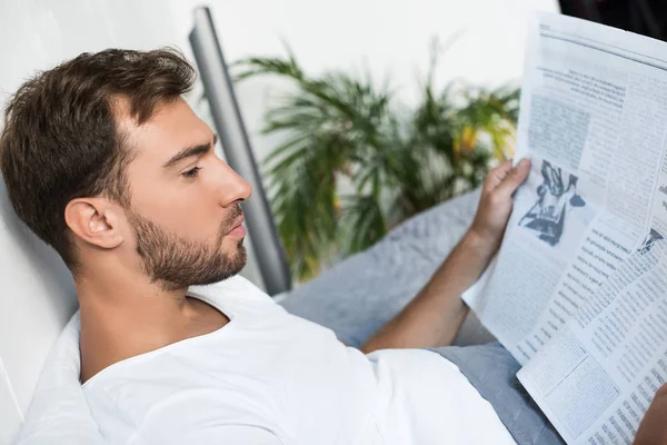 Άντρας στο κρεβάτι, διαβάζοντας εφημερίδα — Φωτογραφία Αρχείου