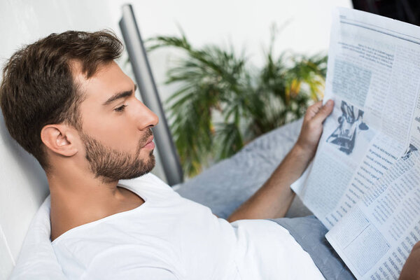 Man in bed reading newspaper