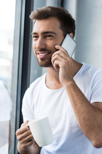 man on phone holding cup of coffee
