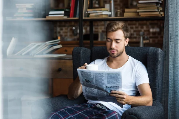 Een man die thuis kranten leest — Stockfoto