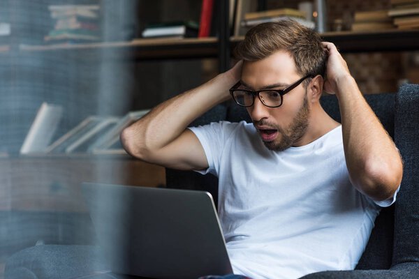 Шокированный человек с ноутбуком
