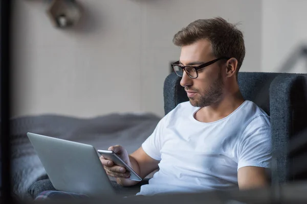 Man with laptop using smartphone — Stock Photo, Image