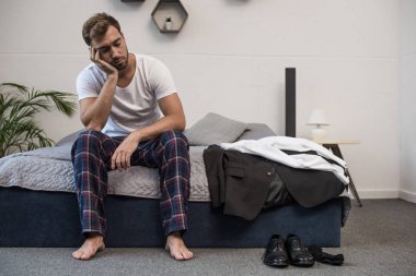 Sleepy man sitting on bed clipart