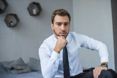 Yatağın üstüne oturan işadamı