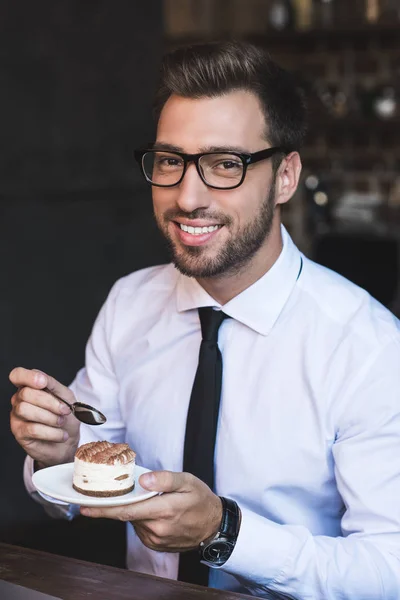 Businessman eating cake at cafe — Stock Photo, Image