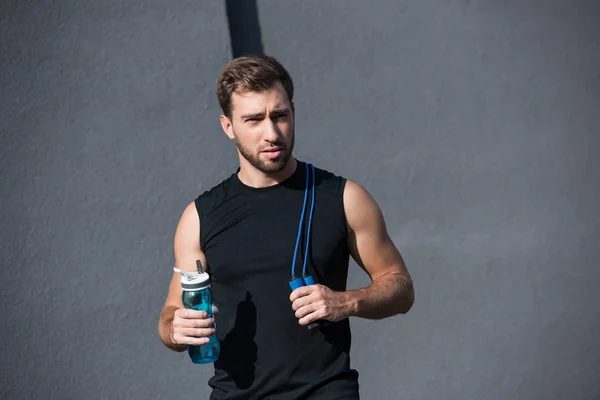 Deportista con saltar la cuerda y botella de agua — Foto de Stock