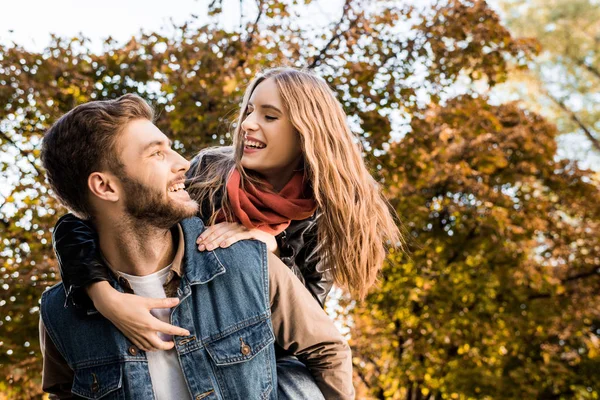 Pareja piggybacking en otoño parque — Foto de Stock