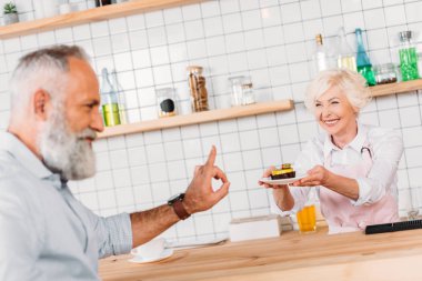 cafe worker offering pastry to man clipart