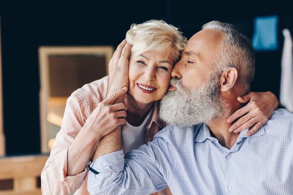 Старший мужчина целует жену
