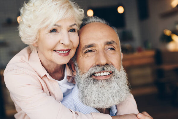 senior woman hugging husband in cafe
