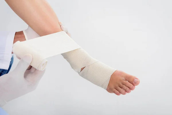 Médico colocando bandagem na perna — Fotografia de Stock
