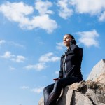 Frau sitzt auf Felsen und hört Musik