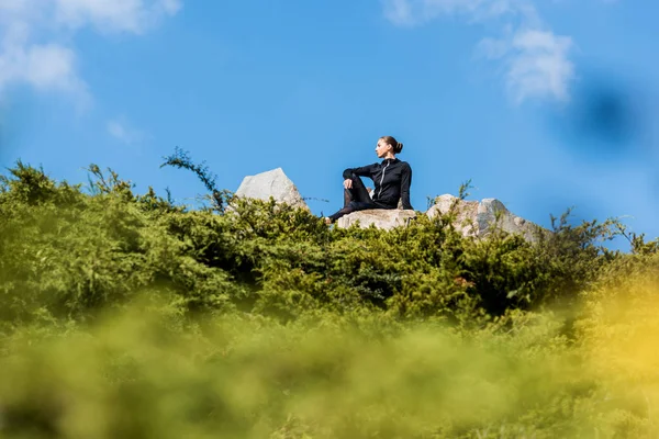 Woman sitting on rocks — Stock Photo, Image