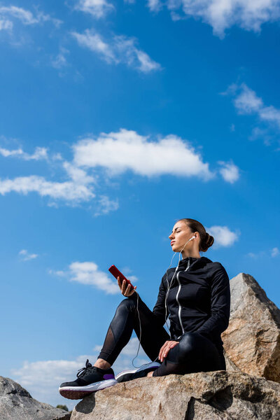 woman sitting on rocks and listening music