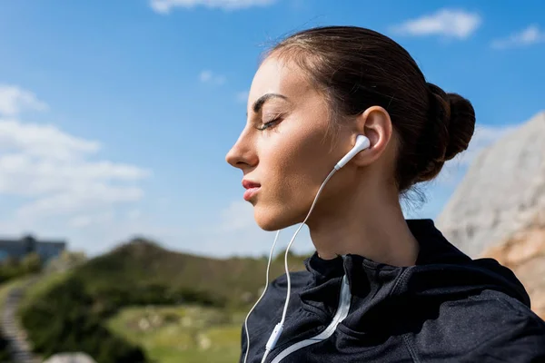 Vrouw luisteren muziek buitenshuis — Stockfoto