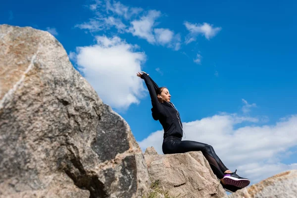 Спортивна жінка сидить на каменях — стокове фото