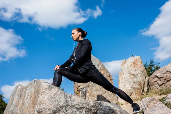 Woman stretching legs on rocks — Stock Photo, Image