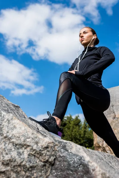 Mujer estiramiento piernas en rocas — Foto de Stock