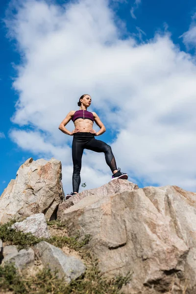 Sportliche Frau steht auf Felsen — kostenloses Stockfoto