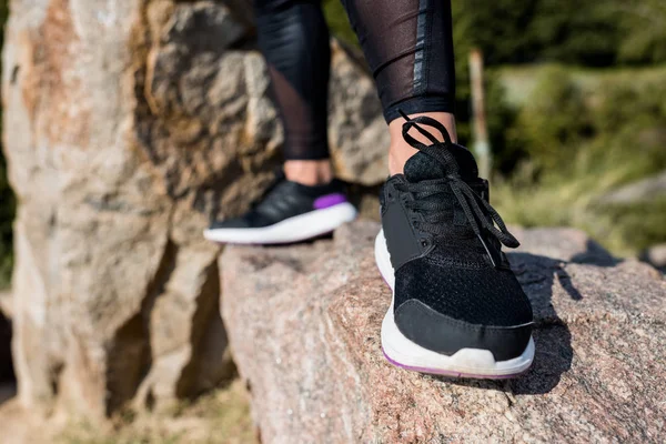 Wanita dalam joging sepatu olahraga berdiri di atas batu — Stok Foto