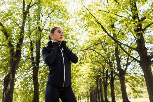 Женщина в спортивной одежде, стоящая в парке — Бесплатное стоковое фото