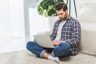 Evde dizüstü bilgisayar kullanan bir adam