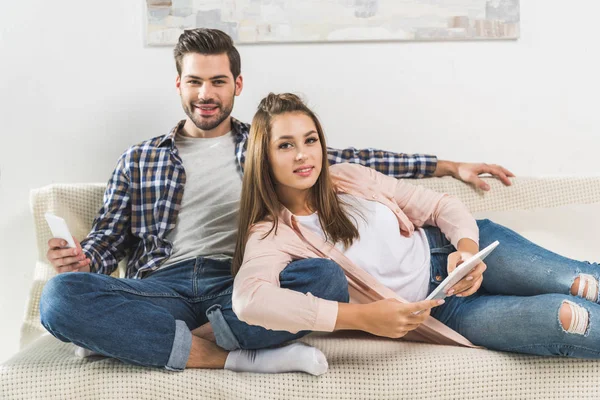 Couple on sofa with devices — Stock Photo, Image