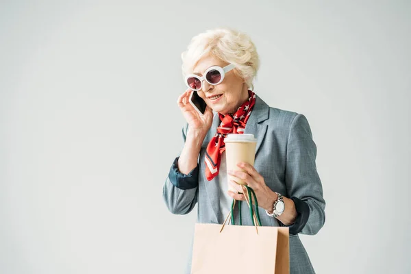 Старшая женщина с сумками для покупок и смартфоном — стоковое фото