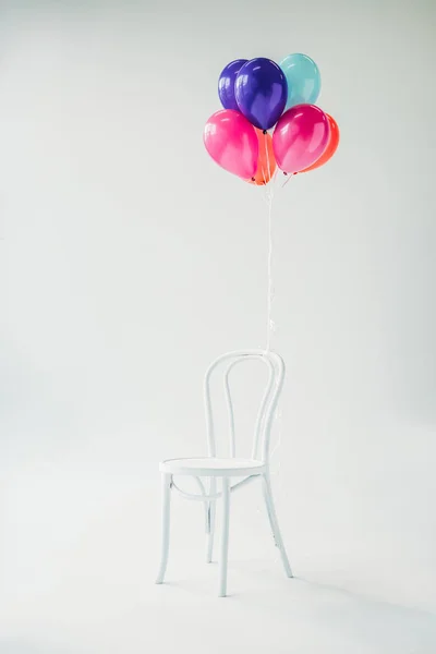 Colorful balloons tied to chair — Stock Photo, Image