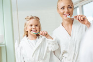 mother and daughter brushing teeth clipart
