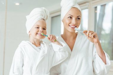 mother and daughter brushing teeth clipart