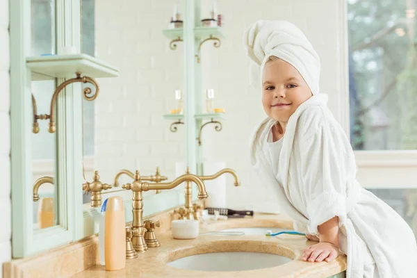 Child in bathrobe brushing teeth — Free Stock Photo