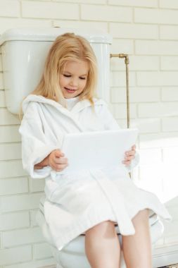 Çocuk tuvalet üzerinde dijital tablet ile
