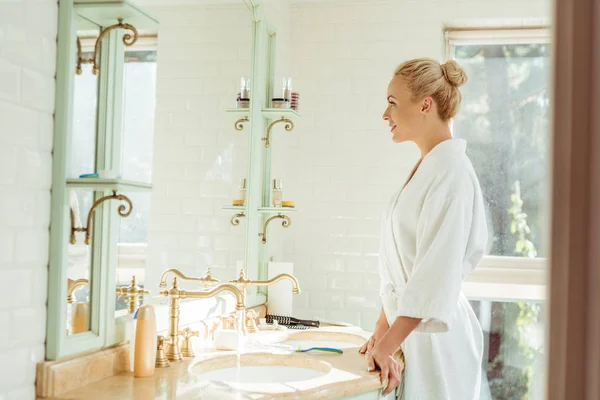 Woman in bathrobe looking at mirror — Stock Photo, Image