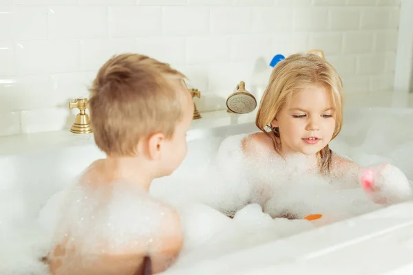 Kids playing in bathtub with foam — Stock Photo, Image
