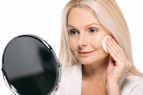 зрелая женщина смотрит в зеркало
