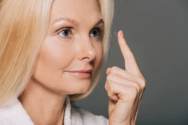 Mature woman applying contact lens — Stock Photo, Image