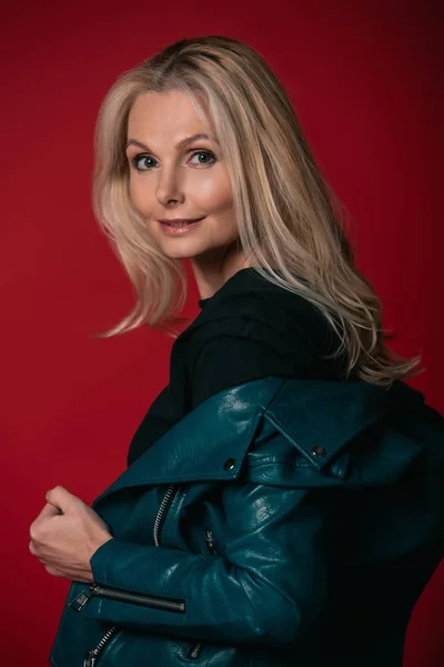 Mature woman taking of leather jacket — Stock Photo, Image