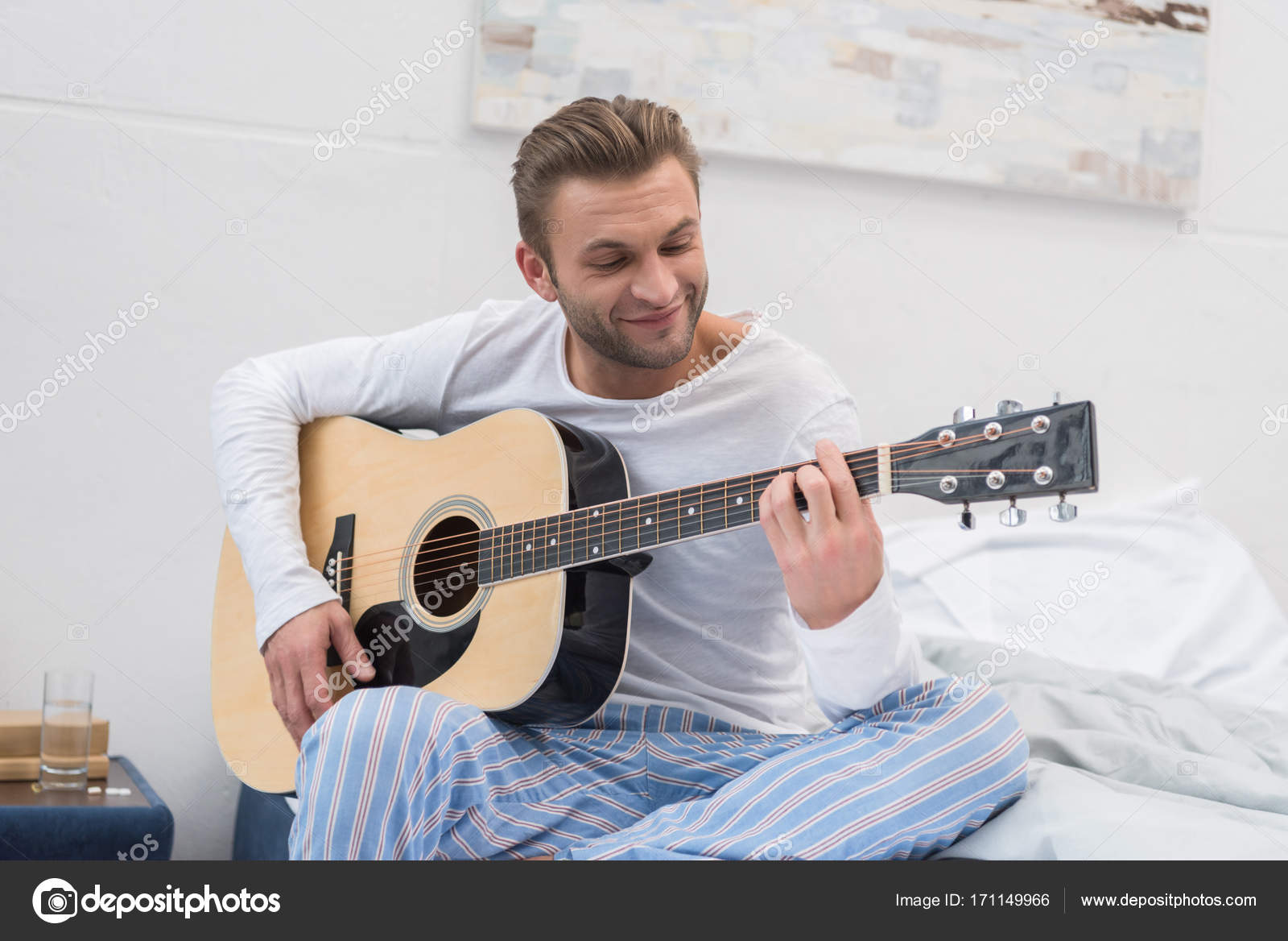 Man playing guitar on bed Stock Photo by ©AllaSerebrina 171149966
