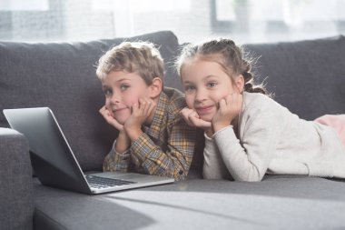 laptop ile kanepede yatan çocuklar