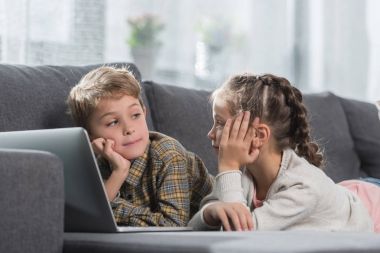 laptop ile kanepede yatan çocuklar  