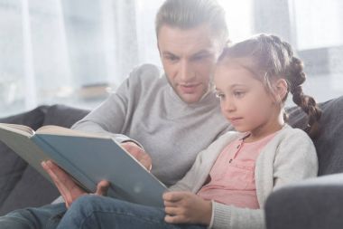 Father teaching daughter read at home clipart