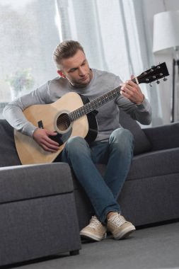Adam akustik gitar çalıyor. 