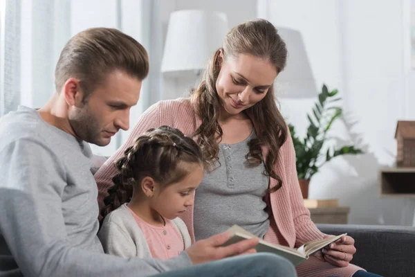 Родители учат дочь читать на дому — стоковое фото