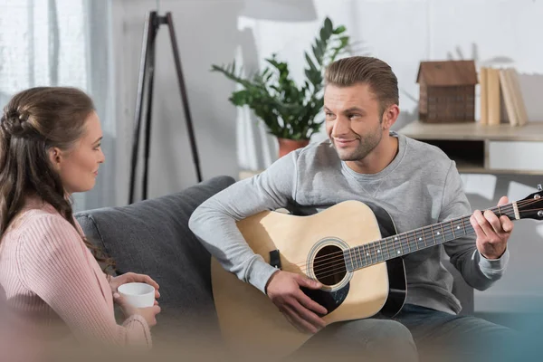 Парень играет на гитаре с девушкой — стоковое фото